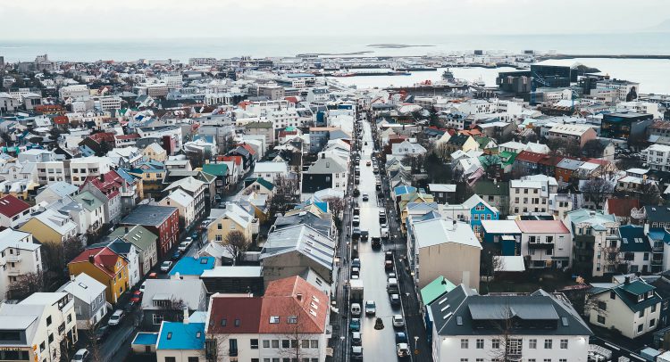 an aerial view of Reykjavík, Iceland during the daytime. It's a crowded town on the water with lots of different coloured buildings.