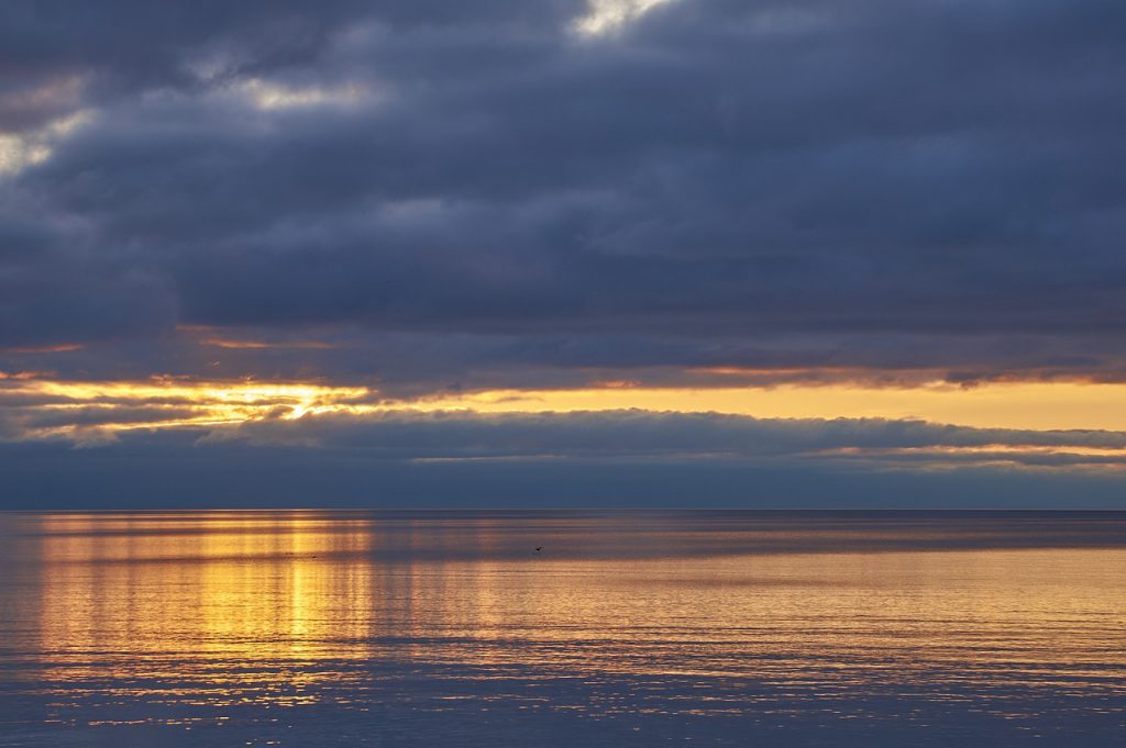 The sun sets behind clouds over a lakefront in Burlington, Ontario.
