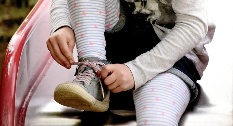 Child tying shoe on a slide
